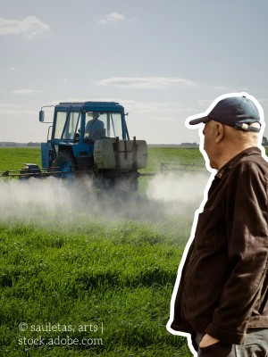 Mann schaut auf einen Traktor, der Pestizide ausbringt