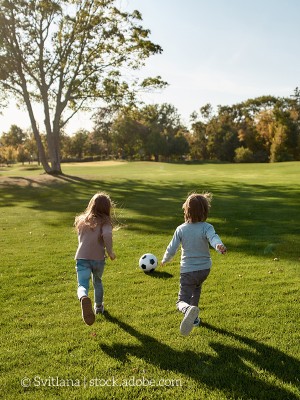 Zwei Kinder spielen mit einem Ball auf einer Wiese