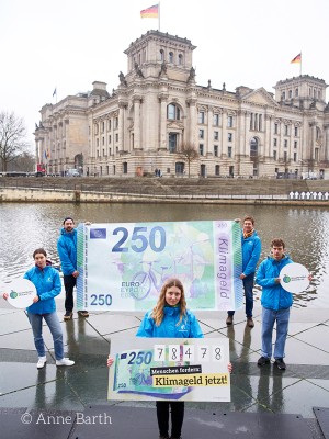Aktion vor dem Reichstag: Aktivist:innen fordern mit XXL-Klimageldschein die Einführung eines Klimageldes.