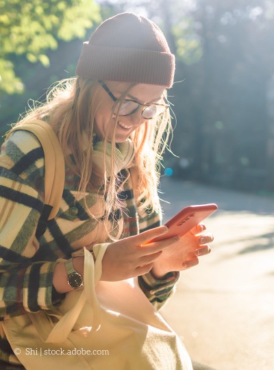 Bild zeigt eine Frau, die auf ihr Smartphone schaut